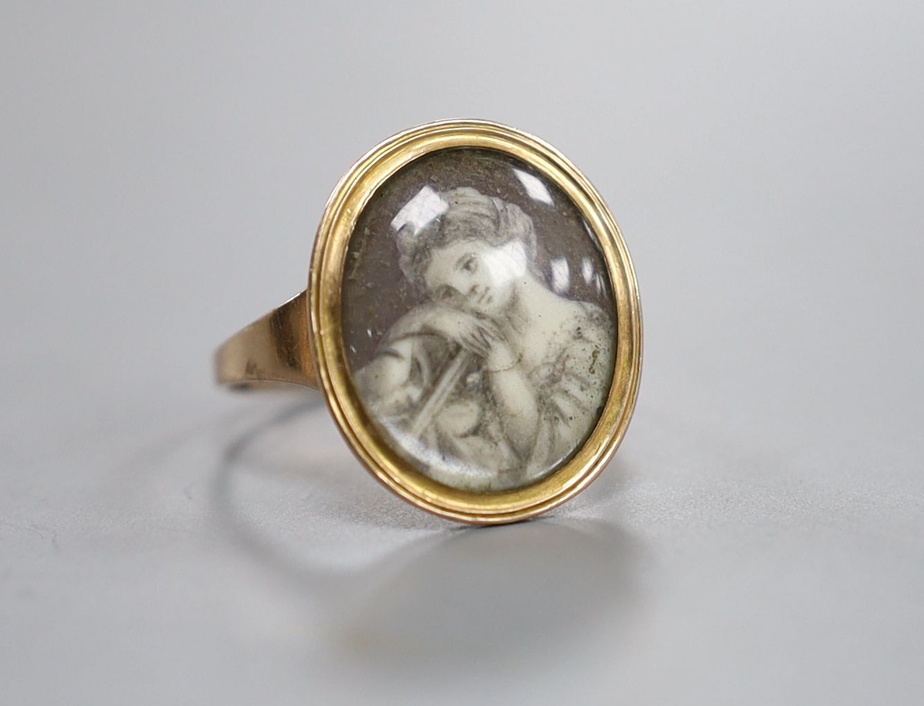 An early 19th century yellow metal ring inset with ivory? panel of a young lady